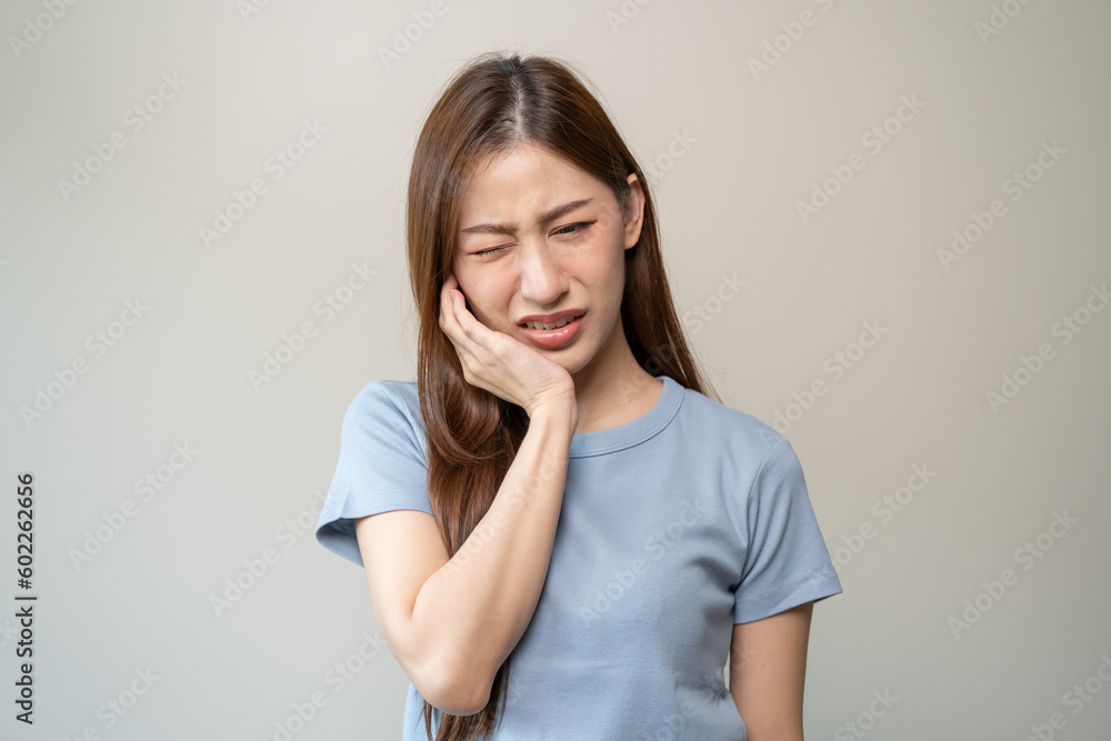 Face expression suffering from sensitive teeth, Asian young woman touching cheek Face expression suffering from sensitive teeth, Asian young woman touching cheek
