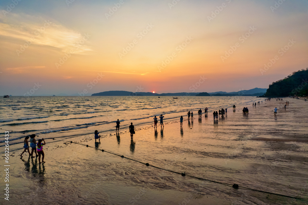 Many people stand and watch the sunset at Ao Nang, Krabi, Thailand