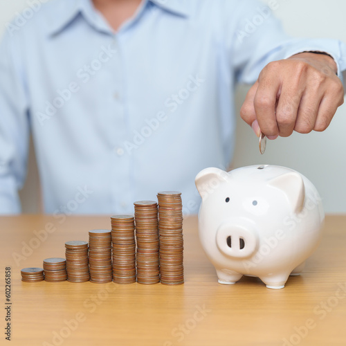 Money Saving for Future Plan, Retirement fund, Pension, Investment, Wealth Business and Financial concepts. hand putting coin into piggy bank on table, Money Counting and stack arrangement for deposit