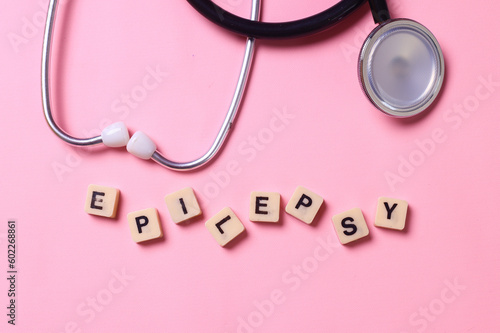 Epilepsy lettering on blocks with stethoscope on pink background. 