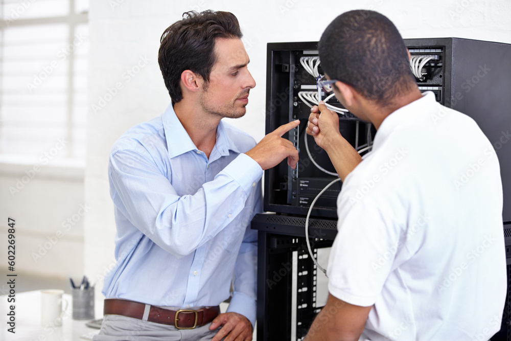 Server room, it support and pointing with a technician talking to a business man about cable connectivity. Network, database and consulting with an engineer showing a male employee a wired connection Server room, it support and pointing with a technician talking to a business man about cable connectivity. Network, database and consulting with an engineer showing a male employee a wired connection