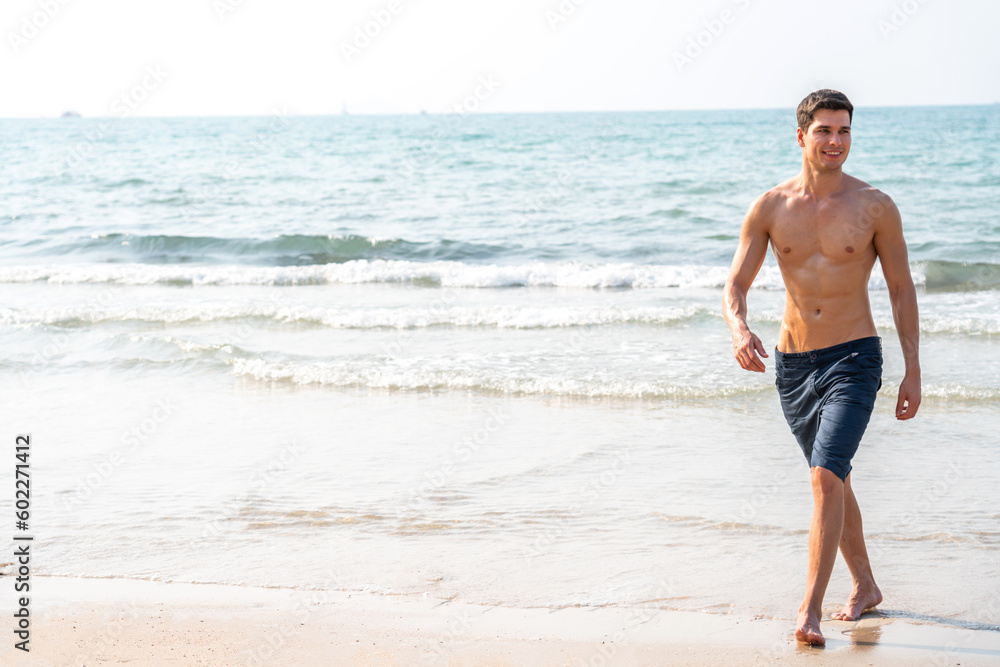 Portrait of smiling happy, relax handsome sexy man, male showing muscular fit body enjoying and relax standing on the tropical sea, beach.Summer vacations and travel