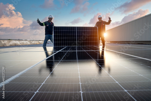 Team of technicians installing solar panels Two young technicians install large solar photovoltaic panels on a tall steel platform on Installing an external solar system