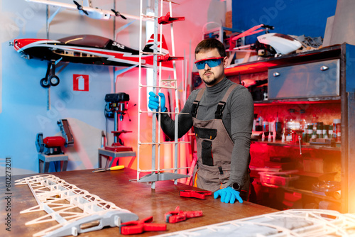 Young male engineer or technician posing in lab. Aircraft capable of GPS surveillance. Look at camera. Carbon. photo