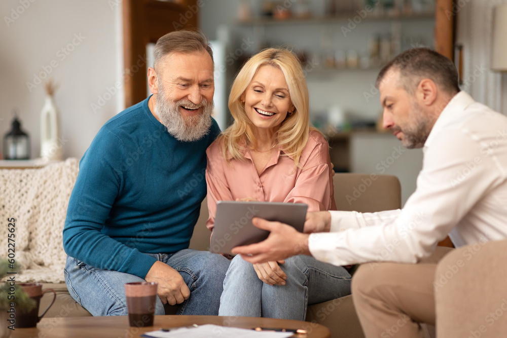Professional Agent Showing Tablet To Excited Senior Couple At Home Professional Agent Showing Tablet To Excited Senior Couple At Home