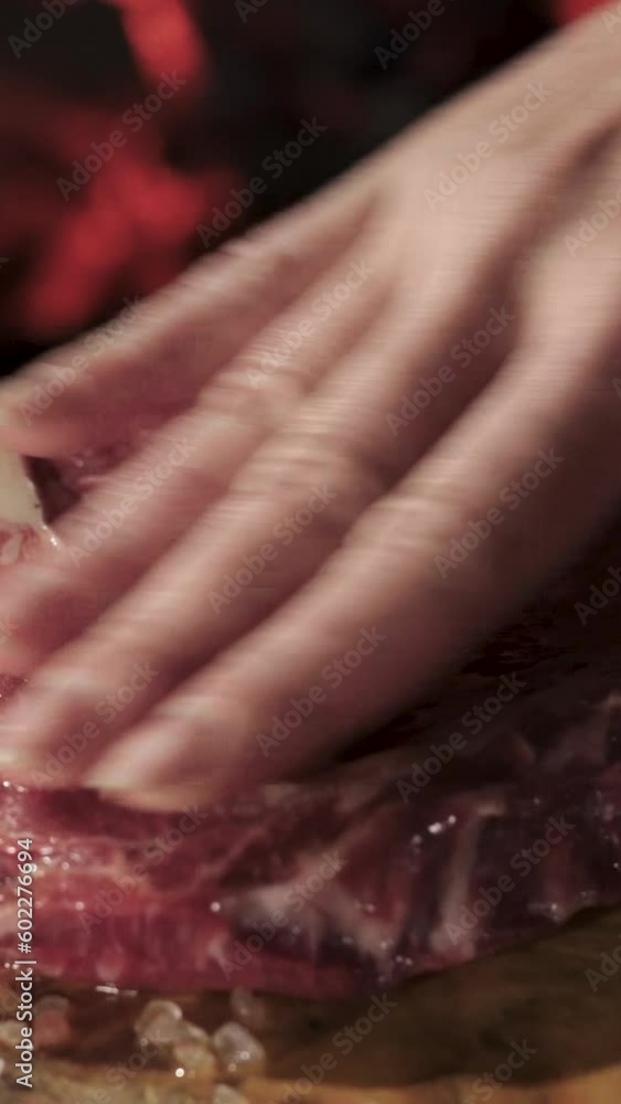Steak on a wooden tray against the background of fire. I rub with spices. Vertical video. Steak on a wooden tray against the background of fire. I rub with spices. Vertical video.