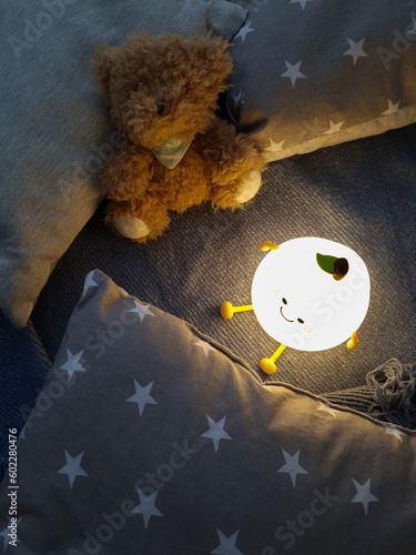 Kids' night light among pillows and toys. Turned on the night light. Cozy shelter for a little toddler. A cute flashlight that illuminates the nursery room.
