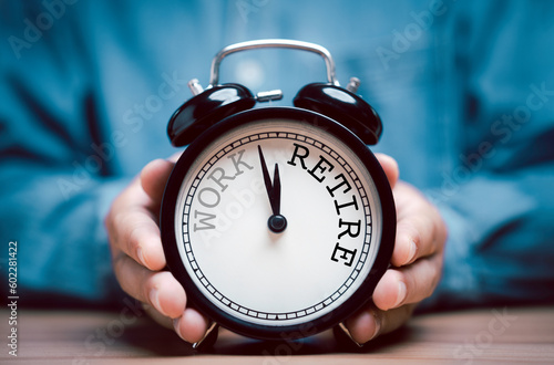 Businessman holding black alarm clock with clockwise countdown from work to retirement.