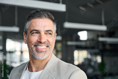 Happy middle aged business man ceo entrepreneur standing in office. Smiling mature confident professional executive manager, confident businessman leader looking away, headshot close up portrait.