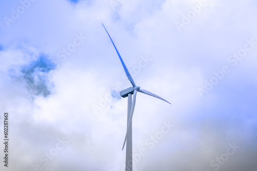 Wind turbine generating electricity clean energy with cloud and sunlight background on the sky. Clean energy concept. © Elena