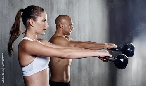 Obraz Fitness, people and weightlifting with kettlebell for arm workout or intense exercise together at the gym. Serious man and woman lifting weight for strong exercising, power or strength in training