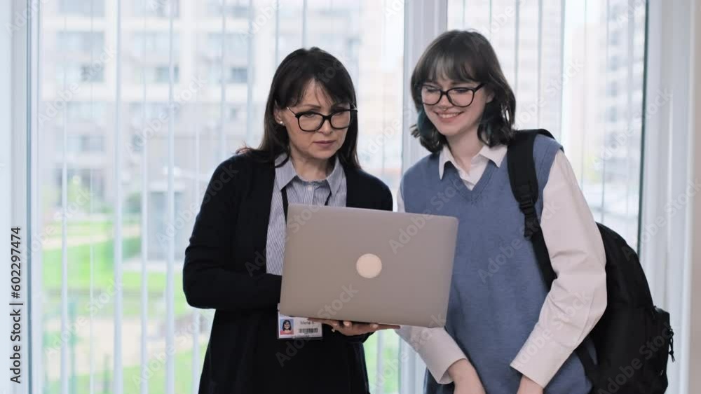Female teacher and girl college student talking looking at laptop screen Female teacher and girl college student talking looking at laptop screen