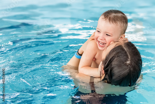joyful baby swims in the pool with his mother, parents teach child to swim in children's pool