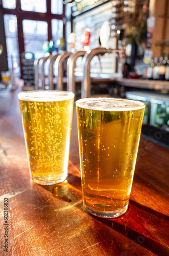 Fotografie Close up of pint glass of lager on the bar of a traditional English pub in the U