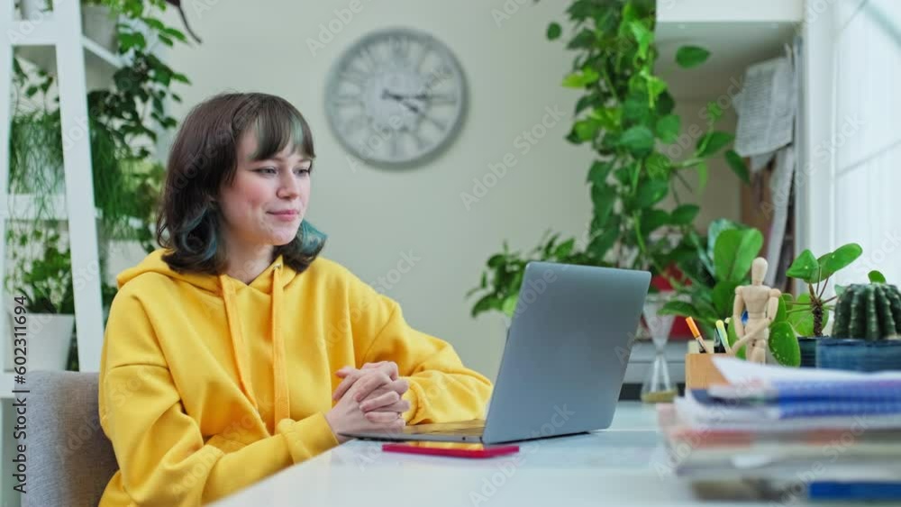 Cheerful teenage girl at home having video call on laptop Cheerful teenage girl at home having video call on laptop