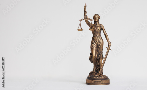 themis goddess of justice statuette on light background. symbol of the law with scales and sword in his hands. legal company or university of law and judicial structure. bar association and human photo