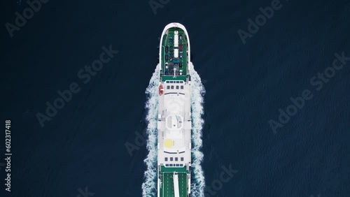 Top down aerial drone view on transportation logistics ferry cruise move through deep blue water with passengers and vehicles on board photo