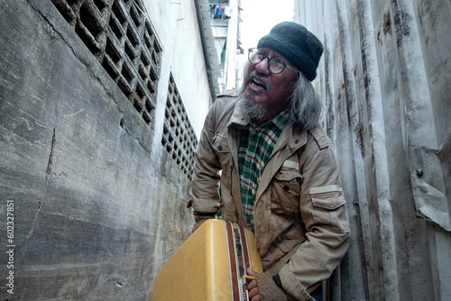 Homeless old man in narrow and dirty alley, with large luggage, unemployment and homeless people concept © chomplearn_2001