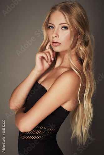 Beauty, face and portrait of a woman in studio with makeup, cosmetics and long hair. Headshot of a female aesthetic model with a natural glow, sexy style and seductive pose on a grey background
