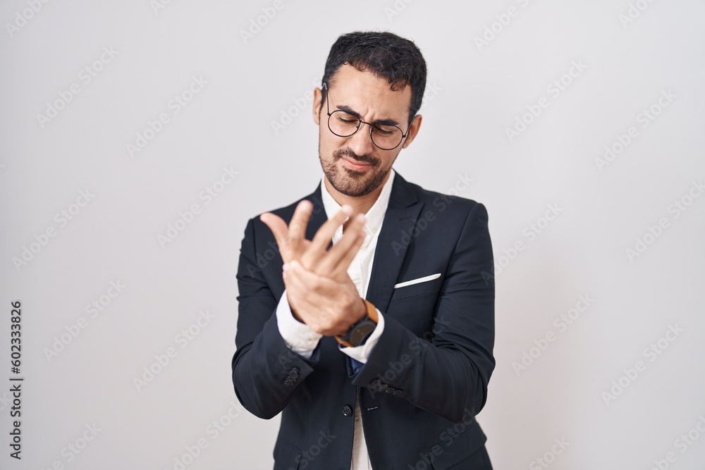 Handsome business hispanic man standing over white background suffering pain on hands and fingers, arthritis inflammation