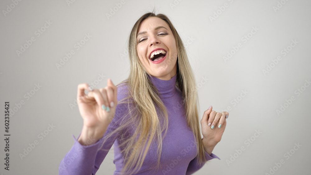 Young blonde woman smiling confident dancing over isolated white background Young blonde woman smiling confident dancing over isolated white background