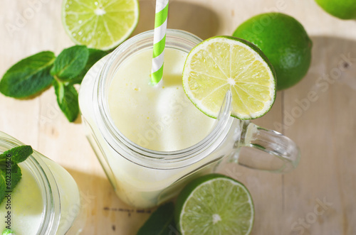 Brazilian Lemonade, Refreshing Creamy Lemonade or Limeade with Lime Slices and Mint on Bright Beige Background