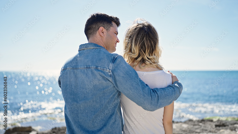 Man and woman couple hugging each other backwards at seaside