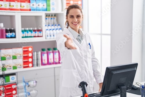 Young woman pharmacist with welcome expression at pharmacy