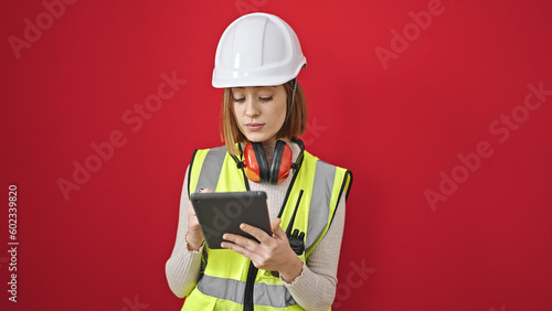 Young blonde woman architect drawing on touchpad with serious expression over isolated red background