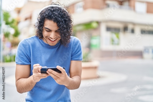 Young latin man smiling confident watching video on smartphone at street