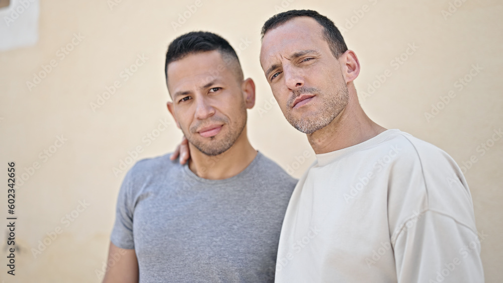 Two men couple standing together with relaxed expression at street Two men couple standing together with relaxed expression at street