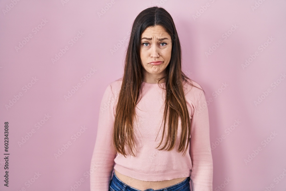 Young brunette woman standing over pink background depressed and worry for distress, crying angry and afraid. sad expression. Young brunette woman standing over pink background depressed and worry for distress, crying angry and afraid. sad expression.