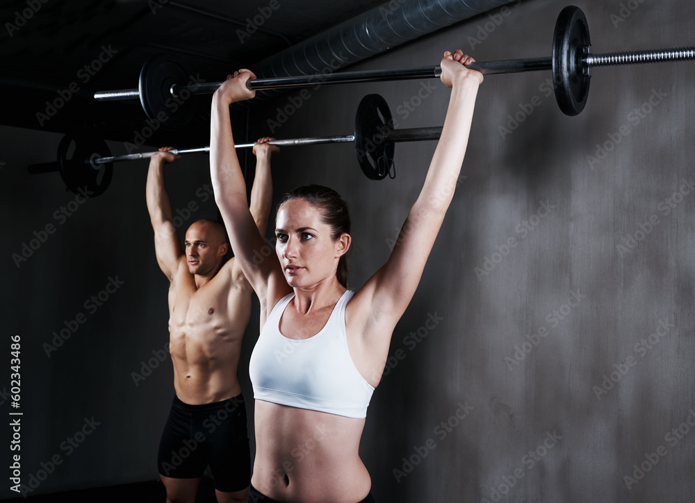 Naklejka premium Fitness, people and weightlifting with barbell for intense training, exercise or bodybuilding at gym. Fit, active and strong woman and man lifting weight for strength, arm muscle or workout together