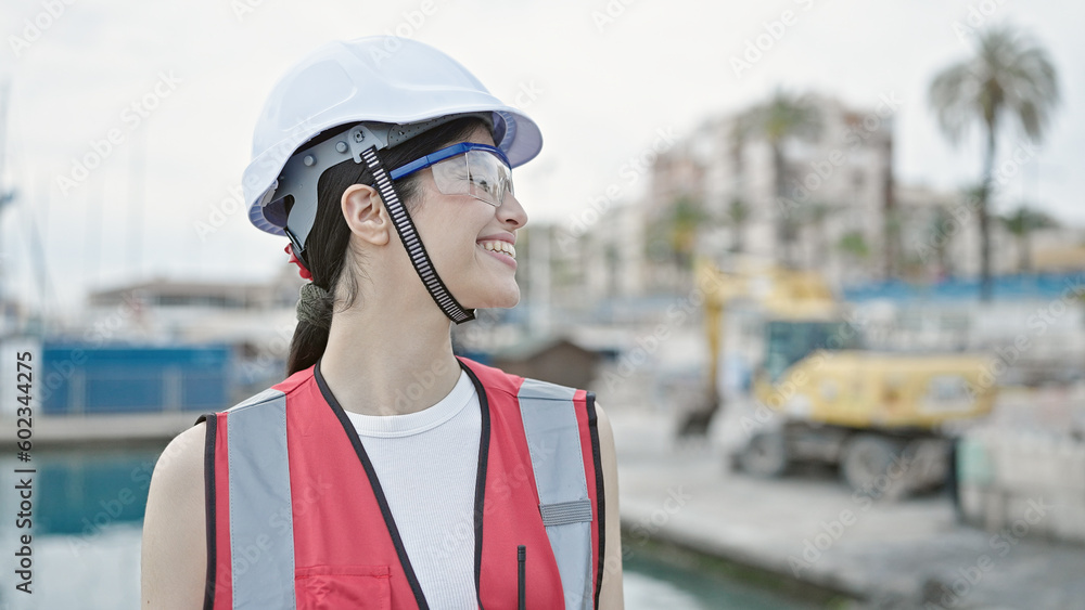 Young beautiful hispanic woman builder smiling confident standing at seaside