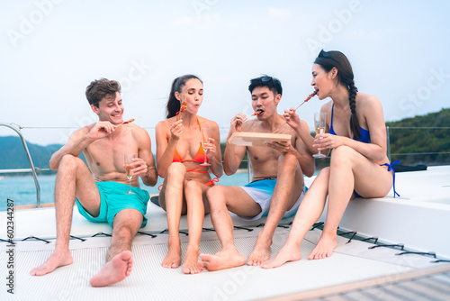 happy man in swimwear and woman in bikini having laugh fun in summer trip with friends group by eat bar-b-q grill and wine party drink, friendship vacation travel on sailboat yacht at the ocean sea © chokniti