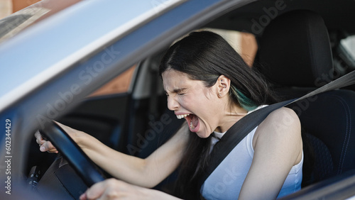 Young beautiful hispanic woman stressed driving car at street © Krakenimages.com
