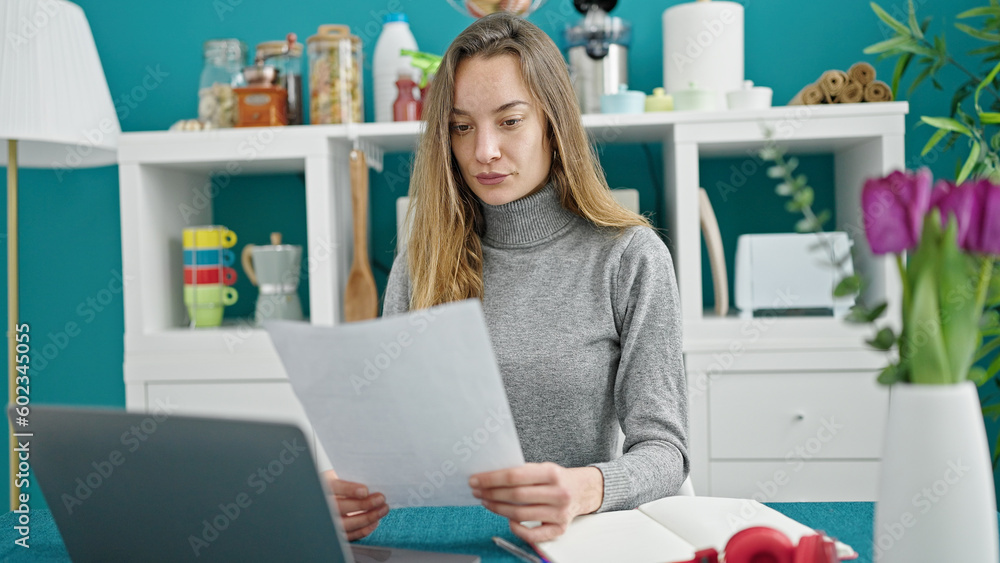 Young caucasian woman reading document with serious expression at dinning room Young caucasian woman reading document with serious expression at dinning room