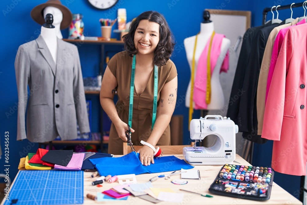 Young woman tailor cutting cloth at sewing studio