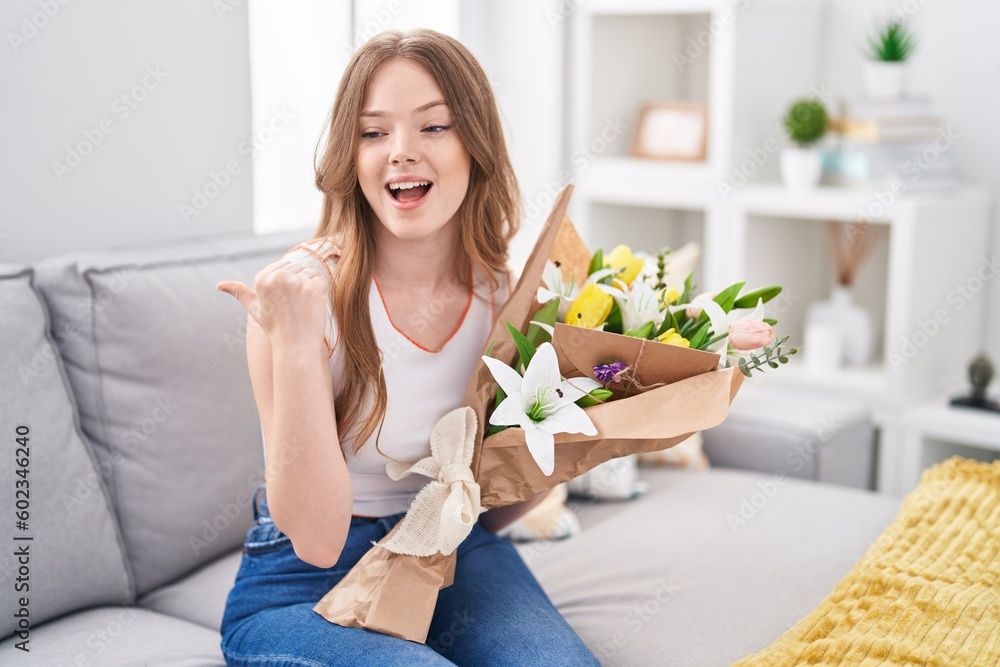 Caucasian woman holding bouquet of white flowers pointing thumb up to the side smiling happy with open mouth