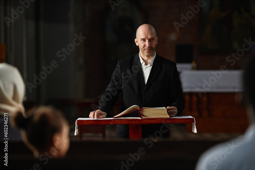 Fotobehang Mature pastor reading Bible for believers while standing at altar in church