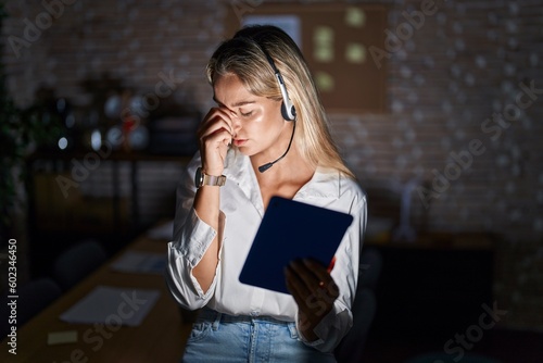 Young blonde woman working at the office at night tired rubbing nose and eyes feeling fatigue and headache. stress and frustration concept.