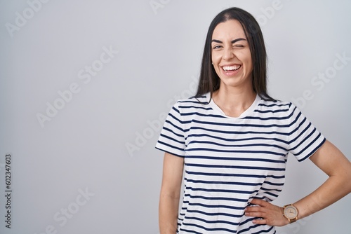 Young brunette woman wearing striped t shirt winking looking at the camera with sexy expression, cheerful and happy face.