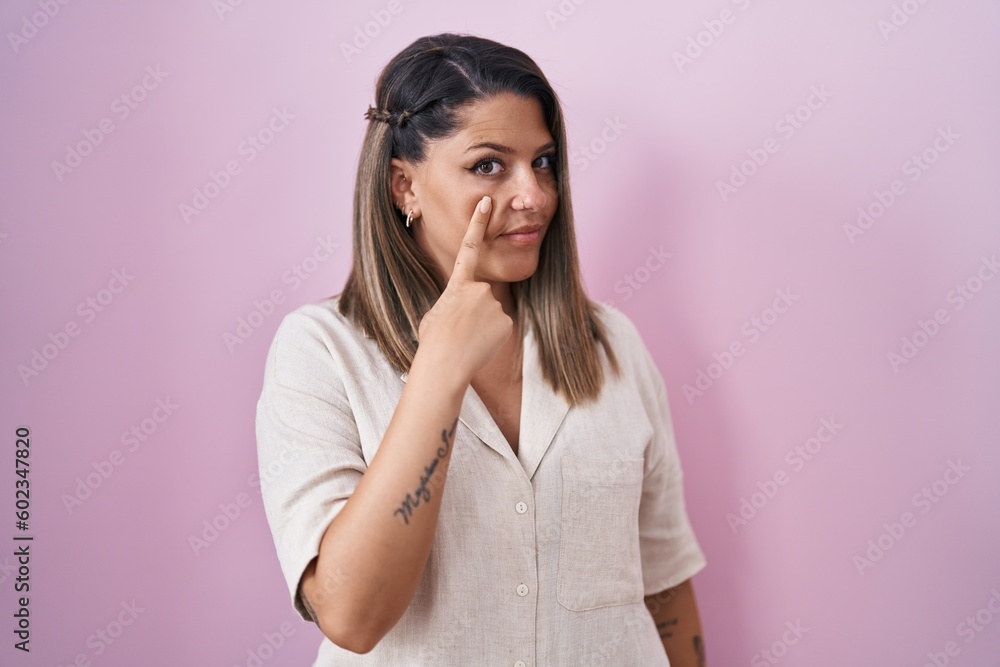 Blonde woman standing over pink background pointing to the eye watching you gesture, suspicious expression Blonde woman standing over pink background pointing to the eye watching you gesture, suspicious expression