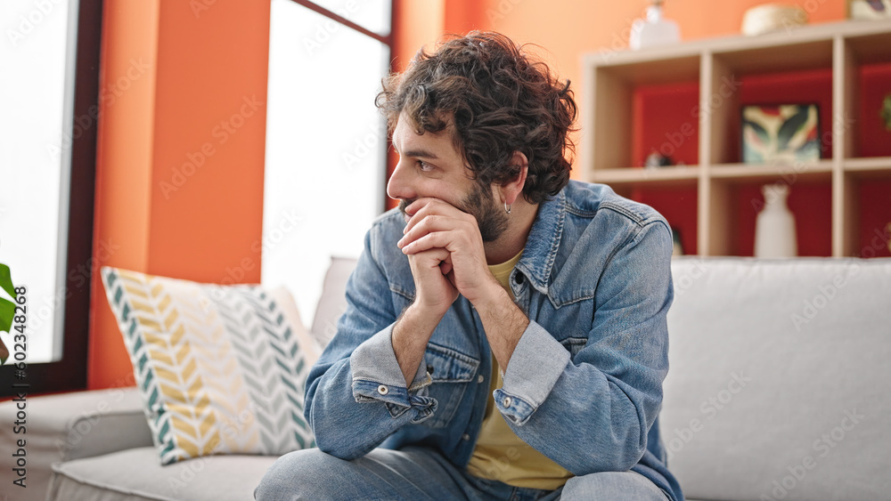 Young hispanic man stressed sitting on sofa at home Young hispanic man stressed sitting on sofa at home