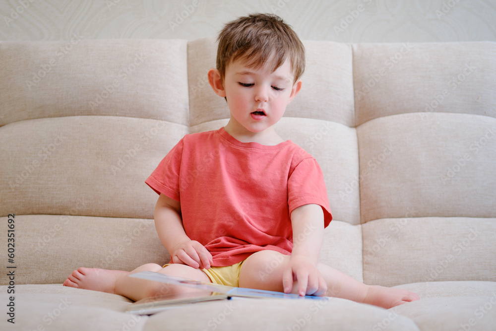 The cute baby is playing with the colorful picture book, flipping through the pages and touching the pictures. The little child reads book. Kid aged about two years (one year ten months) The cute baby is playing with the colorful picture book, flipping through the pages and touching the pictures. The little child reads book. Kid aged about two years (one year ten months)