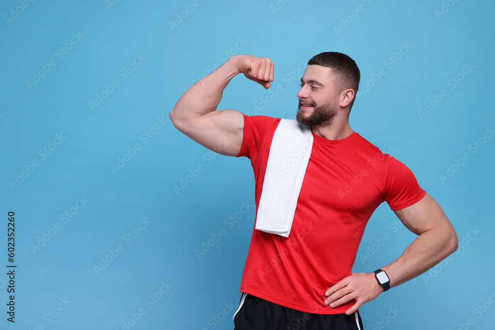 Handsome sportsman with white towel showing muscles on light blue background, space for text Handsome sportsman with white towel showing muscles on light blue background, space for text