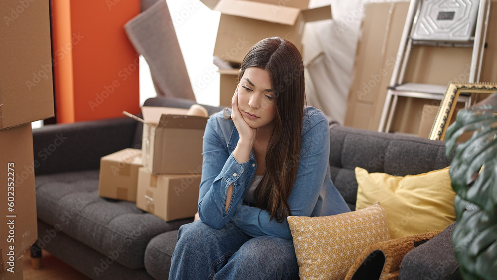 Young beautiful hispanic woman sitting on sofa with unhappy expression at new home Young beautiful hispanic woman sitting on sofa with unhappy expression at new home