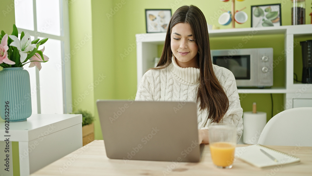 Young beautiful hispanic woman using laptop sitting on table at home Young beautiful hispanic woman using laptop sitting on table at home