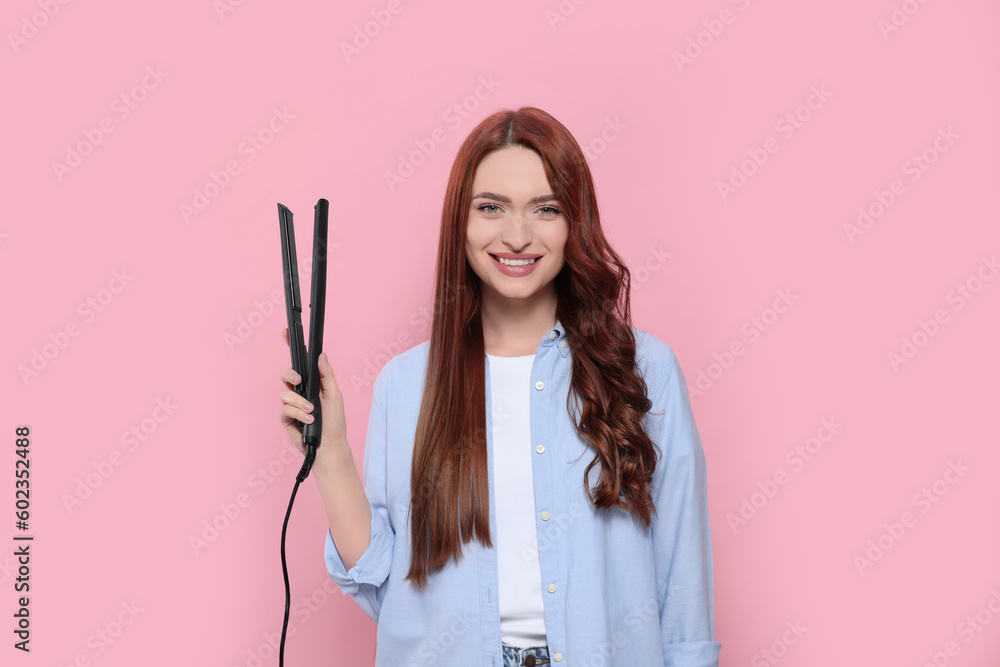 Beautiful woman with hair iron on pink background Beautiful woman with hair iron on pink background