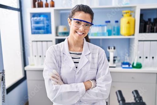 Young beautiful hispanic woman scientist smiling confident standing with arms crossed gesture at laboratory